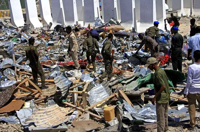 Somali soldiers filter through the debris of a destroyed building near the scene of a suicide car bomb attack in Mogadishu, Somalia, Monday, January 2, 2017. A suicide bomber detonated an explosives-laden vehicle at a security checkpoint near Mogadishu's international airport Monday, killing at least three people, a Somali police officer said. (Photo by Farah Abdi Warsameh/AP Photo)