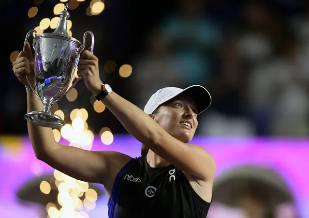Poland's Iga Swiatek raisess her trophy on the podium after winning the WTA Finals Championship women's singles final tennis match in Cancun, Mexico on November 6, 2023. (Photo by Claudio Cruz/AFP Photo)