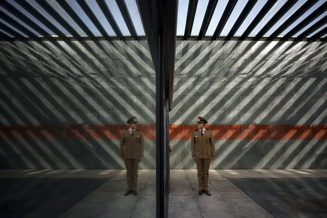 A Romanian serviceman is reflected in a glass, left, as he stands inside the Holocaust memorial, backdropped by names of victims engraved in rusty metal plates, during the National Holocaust Remembrance Day commemorations in Bucharest, Romania, Monday, October 9, 2023, the date when, in 1941, the deportations of Jews and Roma began in the country. About 280,000 Romanian Jews and 11,000 Romanian Roma, or Gypsies, were deported and killed during WWII when Romania was ruled by a pro-Nazi regime. (Photo by Andreea Alexandru/AP Photo)