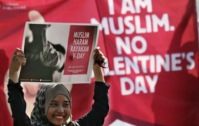 A Muslim girl displays posters “Muslims forbidden to celebrate Valentine's Day” during a protest against Valentine's Day in Jakarta, Indonesia, Sunday, February 14, 2016. Dozens of activists staged the protest calling on Muslims to avoid the celebration of the western holiday, saying that it's against Islamic teachings and could lead to forbidden sexual relations. (Photo by Achmad Ibrahim/AP Photo)