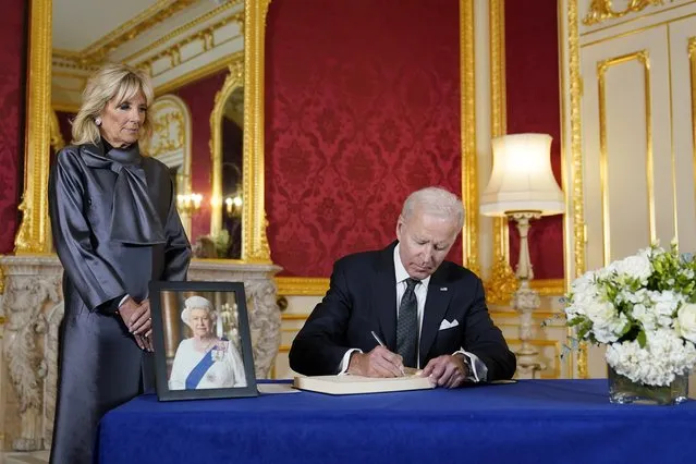 President Joe Biden signs a book of condolence at Lancaster House in London, following the death of Queen Elizabeth II, Sunday, September 18, 2022, as first lady Jill Biden looks on. (Photo by Susan Walsh/AP Photo)