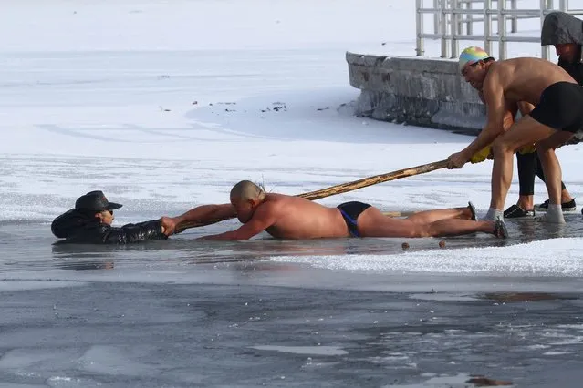 Winter swimmers try to pull man out of icy waters after he was trapped in partially frozen lake at a park in Changchun, China, on December 12, 2013. (Photo by Reuters/Stringer)