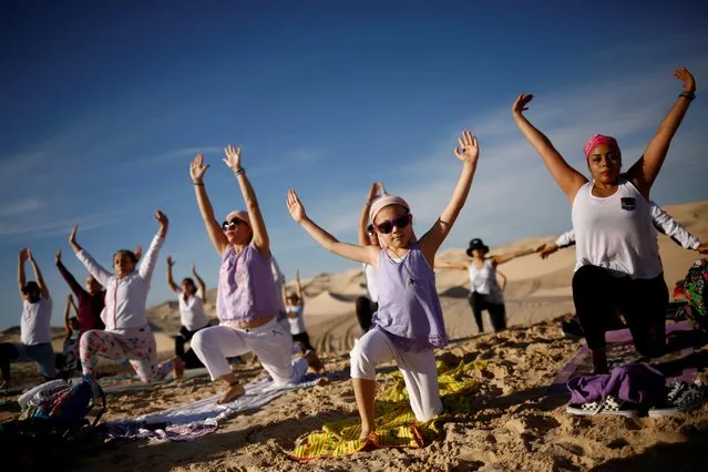 Yoga enthusiasts take part in a class in honor of victims of the coronavirus disease (COVID-19), at the Samalayuca dunes on the outskirts of Ciudad Juarez, Mexico on July 3, 2021. (Photo by Jose Luis Gonzalez/Reuters)