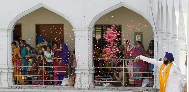 A Sikh devotee throws flower petals as the procession passes by during the Baisakhi festival at Panja Sahib shrine in Hassan Abdel April 13, 2015. (Photo by Caren Firouz/Reuters)