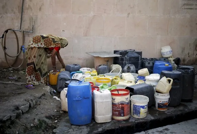 A woman arranges her empty containers as she waits to fill water from a municipal tap in New Delhi, India, February 21, 2016. (Photo by Anindito Mukherjee/Reuters)