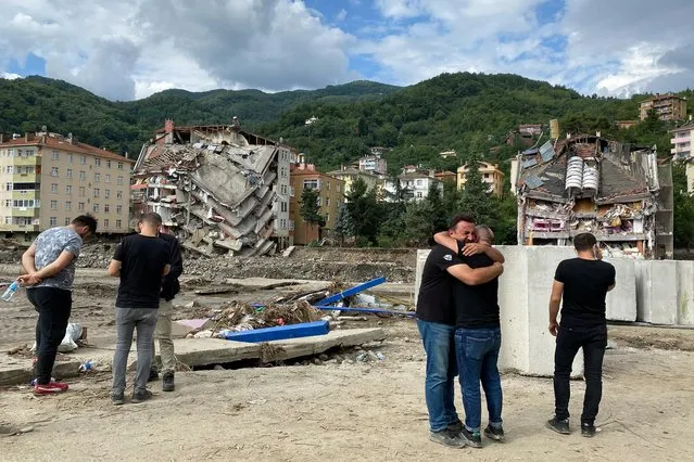 Locals react as they stand near partially collapsed buildings as the area was hit by flash floods that swept through towns in the Turkish Black Sea region, in the town of Bozkurt, in Kastamonu province, Turkey, August 14, 2021. (Photo by Bulent Usta/Reuters)