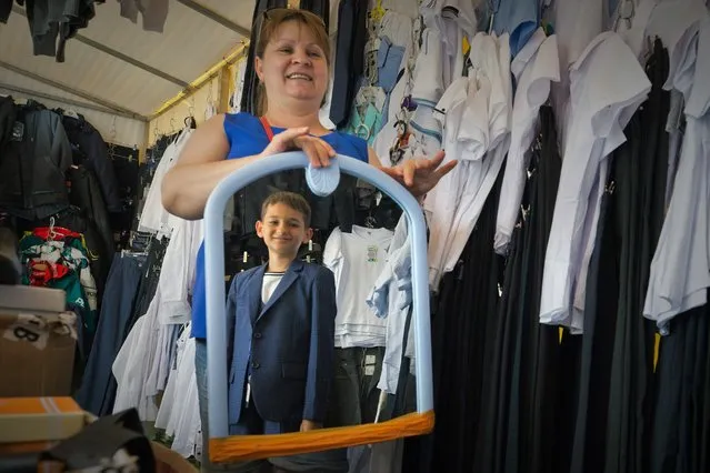 A woman holds a mirror as a teenager tries on school uniform at a back-to-school fair in Trenev Park in the city of Simferopol, Crimea on August 17, 2021. (Photo by Sergei Malgavko/TASS)