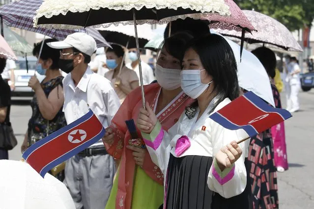 Pyongyang citizens holding North Korean flags watch a performance by an art troupe in front of the Pyongyang Grand Theatre in Pyongyang, North Korea, Tuesday, July 27, 2021, to mark the Korean War armistice anniversary. The leaders of North and South Korea restored suspended communication channels between them and agreed to improve ties, both governments said Tuesday, amid a 2 ½ year-stalemate in U.S.-led diplomacy aimed at stripping North Korea of its nuclear weapons. (Photo by Cha Song Ho/AP Photo)