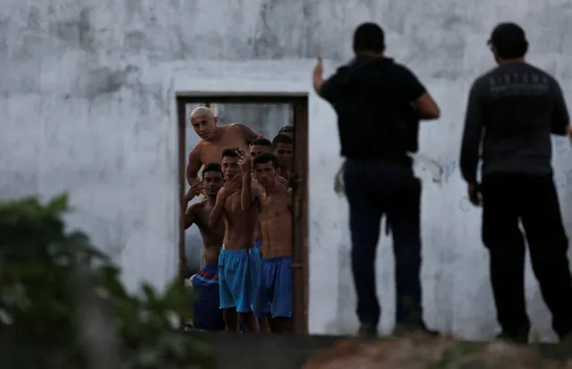 Inmates gesture in front of police officers after they delivered meals to them during an uprising at Alcacuz prison in Natal, Rio Grande do Norte state, Brazil, January 23, 2017. (Photo by Nacho Doce/Reuters)