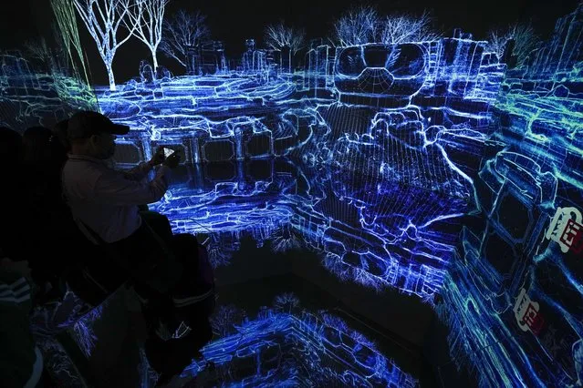 A visitor uses a smartphone to film an audio-visual art installation of ruined Old Summer Palace, at the China Beijing International High-Tech Expo in Beijing, Sunday, September 26, 2021. The annual expo is a showcase for some of China's domestic technological innovations. (Photo by Andy Wong/AP Photo)