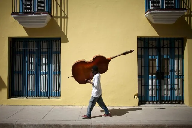 Musician Frilal Ortiz carries a cello in downtown Havana, March 16, 2016. (Photo by Alexandre Meneghini/Reuters)