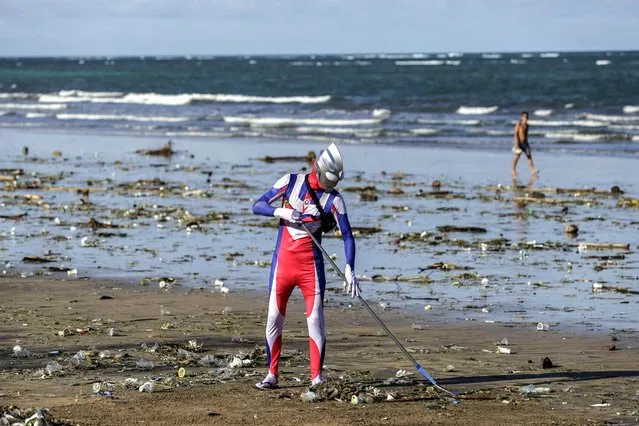 A Japanese tourist cosplayed as Ultraman character cleans up trashes that washed ashore in Kuta Beach, Bali, Indonesia on December 29, 2022. During monsoon Bali's popular Kuta Beach is affected by tons of marine pollution. Trashes of plastic rubbish, woods and other discarded materials washed ashore along the coastline. Coast guards, tourists and locals side by side cleaning the beach as thousands of tourists visit the island during the holiday season of New Year. (Photo by Johannes P. Christo/Anadolu Agency via Getty Images)