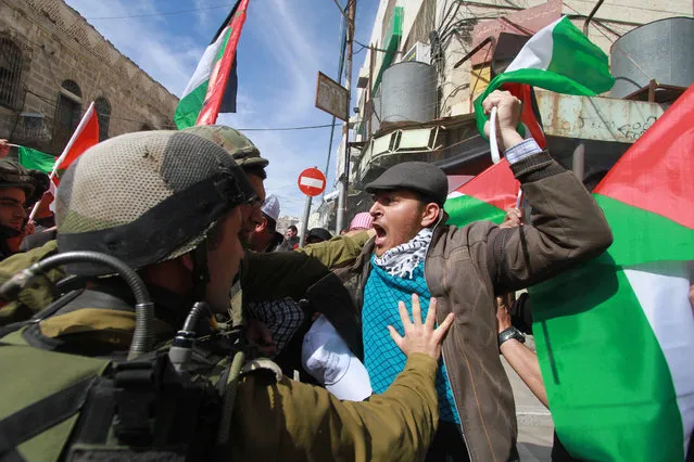 Palestinians scuffle with Israeli soldiers  during a demonstration against the closure of the main downtown street in the center of the West Bank city of Hebron, Friday, February 21, 2014. Shuhada street was shut after a 1994 mosque massacre when a settler shot and killed 29 Muslim worshippers. The military closed it citing security reasons. (Photo by Nasser Shiyoukhi/AP Photo)