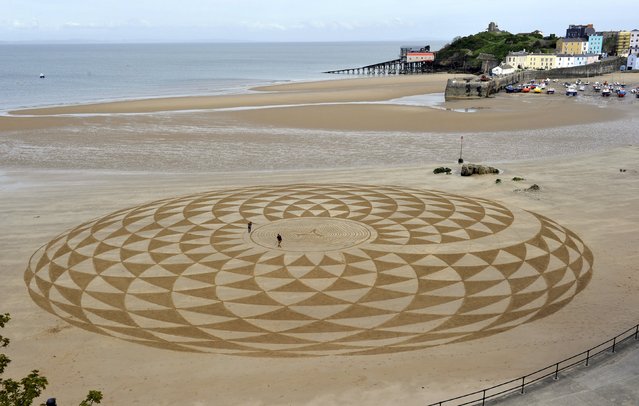 Local artists draw patterns in the sand at low tide on North Beach, Tenby, South Wales, May 7, 2015. (Photo by Rebecca Naden/Reuters)