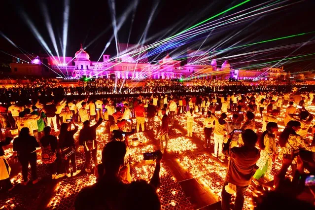People watch a laser show on the banks of the river Sarayu during Deepotsav celebrations on the eve of the Hindu festival of Diwali in Ayodhya on November 3, 2021. (Photo by Sanjay Kanojia/AFP Photo)