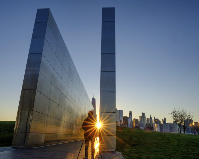A photographer captures the light reflecting off of the Empty Sky Memorial in Jersey City, N.J., Tuesday, April 23, 2019, as the sun rises over the New York City skyline. (Photo by J. David Ake/AP Photo)