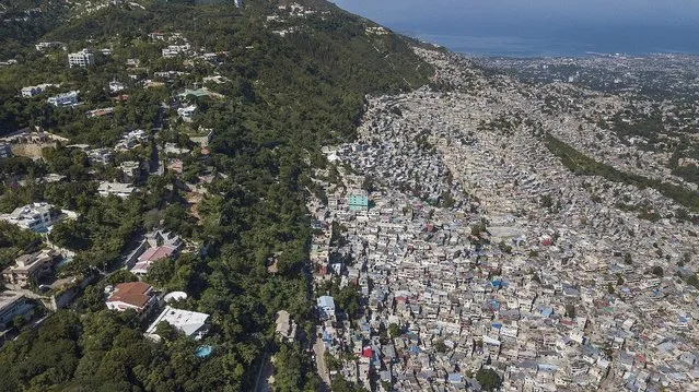 Trees separate an affluent neighborhood, Morne Calvaire, from densely populated homes in the Jalouise neighborhood of Port-au-Prince, Haiti, Friday, November 5, 2021. (Photo by Matias Delacroix/AP Photo)