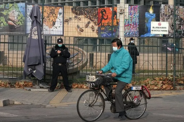 A resident on bicycle past by security personnel outside the U.S. Embassy in Beijing, China on November 16, 2021. China and the U.S. have agreed to ease restrictions on each other's media workers amid a slight easing of tensions between the two sides. (Photo by Ng Han Guan/AP Photo)