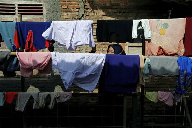 A woman stands among laundry hanging on clotheslines in Muntang village, Purbalingga, Central Java province, Indonesia, November 3, 2021. (Photo by Ajeng Dinar Ulfiana/Reuters)