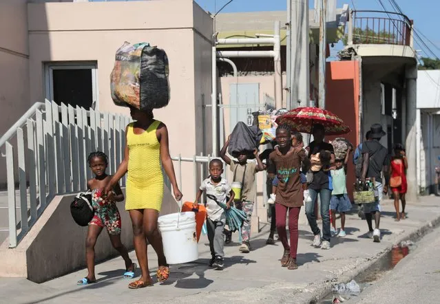 People walk towards a shelter with their belongings fleeing from violence around their homes, in Port-au-Prince, Haiti on March 9, 2024. (Photo by Ralph Tedy Erol/Reuters)