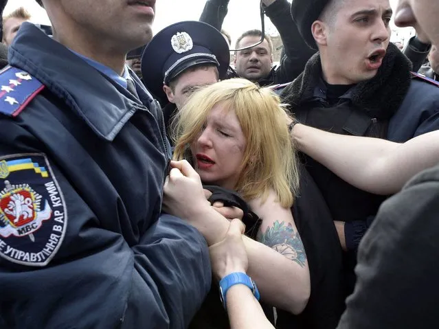 Ukrainian police officers detain a topless activist of the Ukrainian women movement Femen, protesting against the war in front of Cremea's parliament during a pro-Russian rally in Simferopol on March 6, 2014. (Photo by Alexander Nemenov/AFP Photo)
