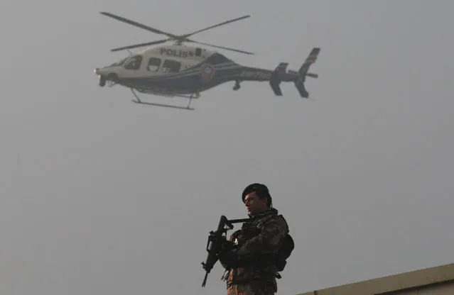A police helicopter flies over as a member of police special forces stands guard during the first hearing of the trial for Turkish soldiers accused of attempting to assassinate Turkish President Tayyip Erdogan on the night of the failed last year's July 15 coup, in Mugla, Turkey, February 20, 2017. (Photo by Kenan Gurbuz/Reuters)