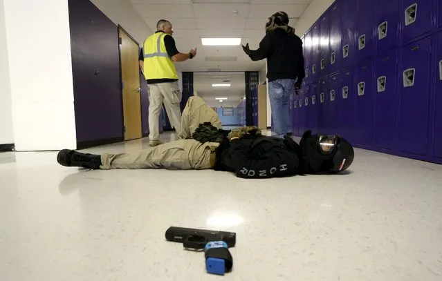 Joe Deedon (L,) president of TAC ONE Consulting, debriefs a student after a scenario with a mock victim (foreground) in a middle school during an Active Shooter Response course offered by TAC ONE in Denver April 2, 2016. (Photo by Rick Wilking/Reuters)