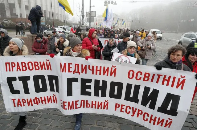 People attend a protest against vaccination process and restrictions connected with coronavirus pandemic for unvaccinated people on the Independence Square in Kiev, Ukraine, 12 December 2021. Protesters demand the lawmakers don't accept the law no. 4142 which considerably extend the rights of the Cabinet of Ministers for imposition of new restrictions during a COVID-19 pandemic. (Photo by Sergey Dolzhenko/EPA/EFE)