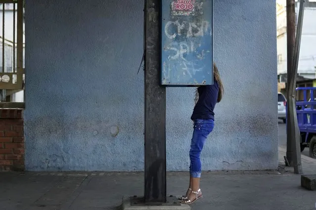 A child plays on a public phone booth in Sabaneta, Venezuela, Friday, January 7, 2022. (Photo by Matias Delacroix/AP Photo)