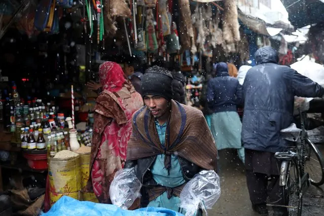 Afghan men walk in a market area during a snowfall in Kabul, Afghanistan, January 3, 2022. (Photo by Ali Khara/Reuters)