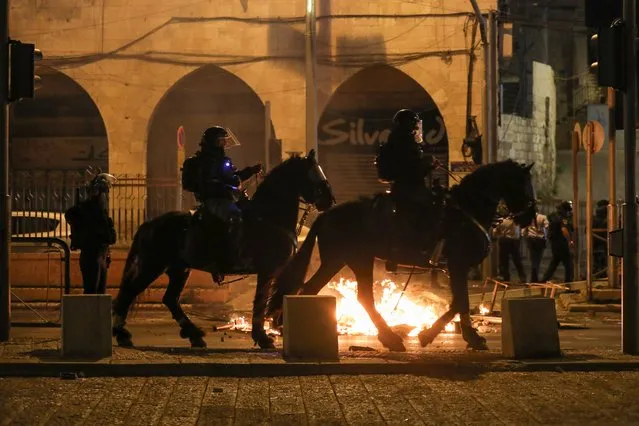 Mounted Israeli police officers ride past a fire during clashes with Palestinians, as the Muslim holy fasting month of Ramadan continues, in Jerusalem, April 22, 2021. (Photo by Ammar Awad/Reuters)