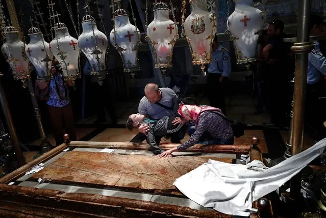 Christian Orthodox pilgrims pray with their handicapped son inside the Church of the Holy Sepulchre in Jerusalems Old City during the Good Friday celebrations, on April 29, 2016. Good Friday is a Christian religious holiday commemorating the crucifixion of Jesus Christ and his death at Calvary. (Photo by Thomas Coex/AFP Photo)