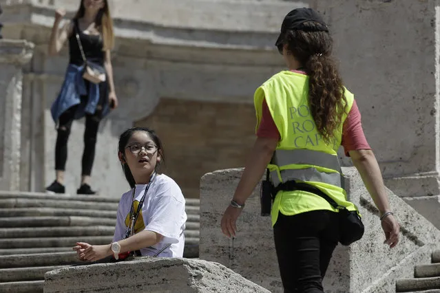 A Police officer asks a girl not to sit on the Spanish Steps, in Rome, Wednesday, August 7, 2019. Police started the enforcement of a law designed to protect monuments and landmarks and are forbidding people from sitting on the Spanish steps since they are considered a monument. (Photo by Gregorio Borgia/AP Photo)