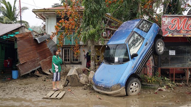 A resident looks at a vehicle swept away due to floodings brought about by super Typhoon Rai in Loboc town, Bohol province, Philippines on December 21, 2021. (Photo by Cheryl Baldicantos/AFP Photo)