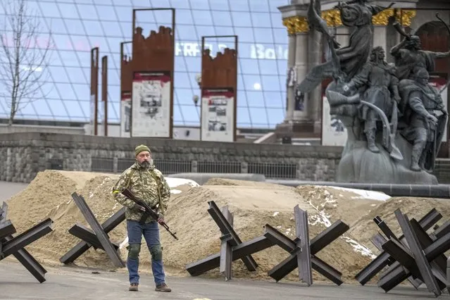 An armed man stands near a barricade during an air raid alarm in Maidan Square, in Kyiv, Ukraine, Tuesday, March 1, 2022. Russian strikes pounded the central square in Ukraine’s second-largest city and other civilian targets, and a 40-mile convoy of tanks and other vehicles threatened the capital. (Photo by Vadim Ghirda/AP Photo)