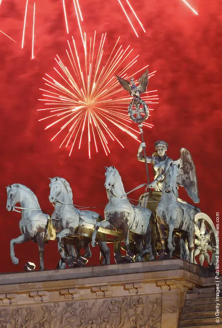 Fireworks explode over the Quadriga statue atop the Brandenburg Gate on New Year's Eve on January 1, 2012 in Berlin
