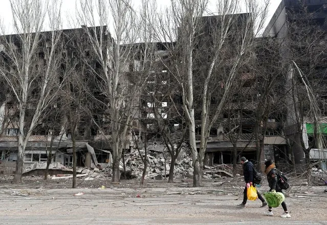 Local residents walk past an apartment building destroyed during Ukraine-Russia conflict in the besieged southern port city of Mariupol, Ukraine on March 31, 2022. (Photo by Alexander Ermochenko/Reuters)