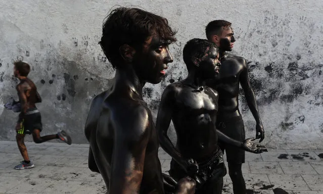 In this photo taken on Friday, September 6, 2019, boys painted with black grease celebrate during the traditional festivities of the Cascamorras festival in Baza, Spain. During the Cascamorras Festival, and according to an ancient tradition, participants throw black paint over each other for several hours every September 6 in the small town of Baza, in the southern province of Granada. The “Cascamorras” represents a thief who attempted to steal a religious image from a local church. People try to stop him, chasing him and throwing black paint as they run through the streets. (Photo by Manu Fernandez/AP Photo)