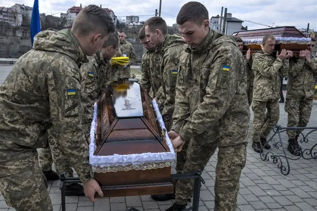 Soldiers prepare to place the Ukrainian flag on the coffin of 41-year-old soldier Simakov Oleksandr, during his funeral ceremony, after he was killed in action, at the Lychakiv cemetery, in Lviv, western Ukraine, Monday, April 4, 2022. (Photo by Nariman El-Mofty/AP Photo)