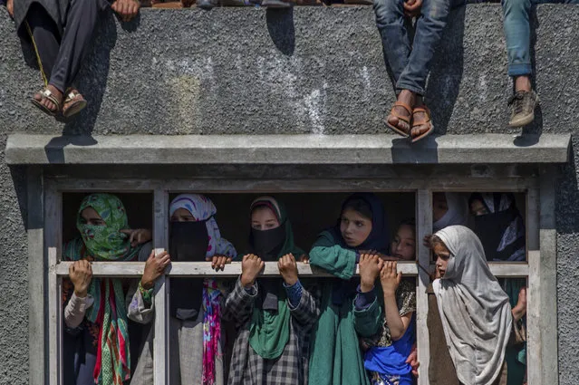 Kashmiri village girls watch the funeral procession of rebel leader Sabzar Ahmed Bhat in Retsuna 45 Kilometers south of Srinagar, Indian controlled Kashmir, Sunday, May 28, 2017. Thousands of people assembled in southern Tral area to take part in the funeral of the rebel leader Sabzar Ahmed Bhat, chanting slogans calling for Kashmir's freedom from Indian rule. (Photo by Dar Yasin/AP Photo)