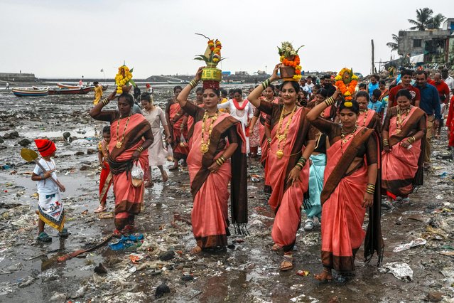 Members of the fishing community make their way through a beach filled with plastic waste to offer coconuts to the ocean to celebrate Narali Pournima, or coconut festival, in Mumbai, India, Monday, August 19, 2024. (Photo by Rafiq Maqbool/AP Photo)