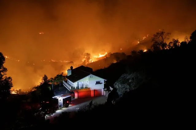 A wildfire burns near a home on Wednesday, May 14, 2014, in San Marcos, Calif. Flames engulfed suburban homes and shot up along canyon ridges in one of the worst of several blazes that broke out Wednesday in Southern California during a second day of a sweltering heat wave, taxing fire crews who fear the scattered fires mark only the beginning of a long wildfire season. (Photo by AP Photo)