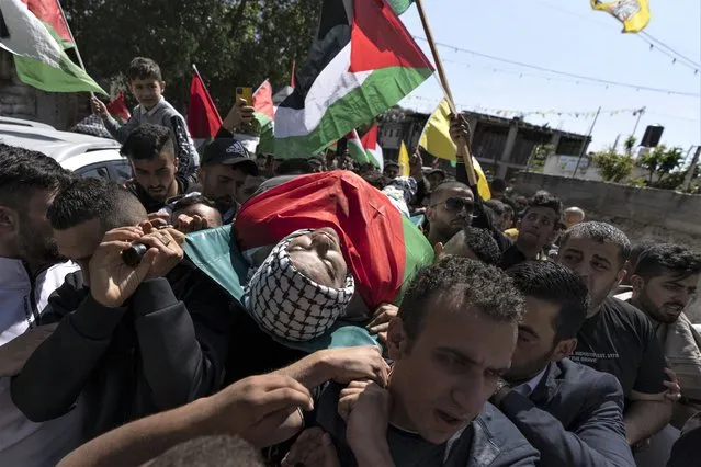 Palestinian mourners carry the body of Muhammad Assaf during his funeral in the West Bank village of Kufr Laqef, near Qalqiliya, Wednesday, April 13, 2022. Israeli forces shot and killed Assaf, 34, during clashes on Wednesday, the Palestinian Health Ministry said, as Israeli troops continued a days-long operation in the occupied West Bank in response to a spate of deadly attacks. (Photo by Nasser Nasser/AP Photo)