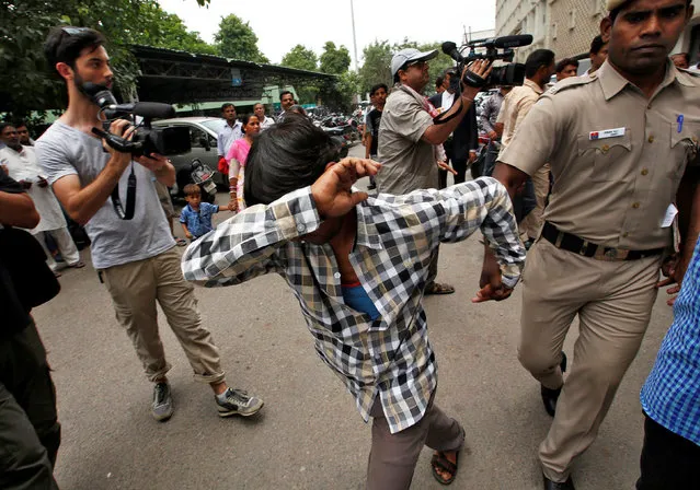 A man convicted for the gang rape of a Danish woman tries to hide his face as he is escorted by a policeman at a court in New Delhi, India, June 9, 2016. (Photo by Adnan Abidi/Reuters)