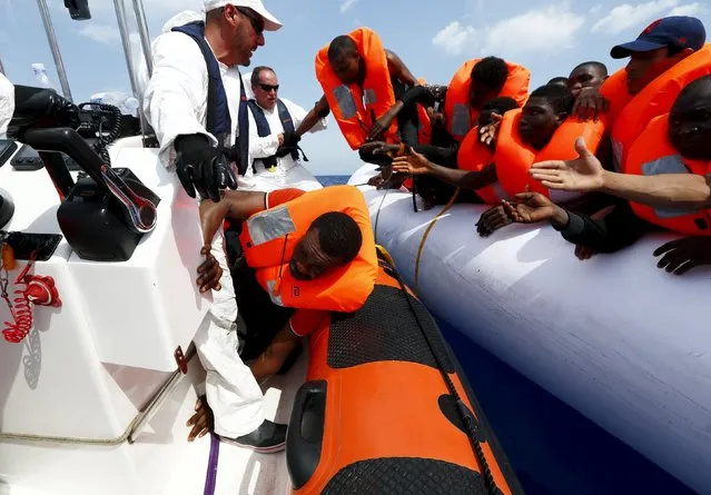 Migrants are helped to cross from their rubber dinghy to a Migrant Offshore Aid Station (MOAS) RHIB (Rigid-hulled inflatable boat) before being taken to the MOAS ship MV Phoenix, some 20 miles (32 kilometres) off the coast of Libya, August 3, 2015. (Photo by Darrin Zammit Lupi/Reuters)
