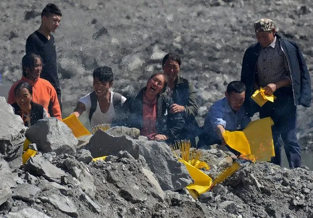 In this photo taken on June 25, 2017, relatives mourn at the site of a landslide in Xinmo village, Diexi town of Maoxian county, Sichuan province. Rescuers searching for more than 90 people missing following the huge landslide in southwest China were ordered to evacuate on June 26 due to the risk of another collapse, state media reported. (Photo by AFP Photo/Stringer)