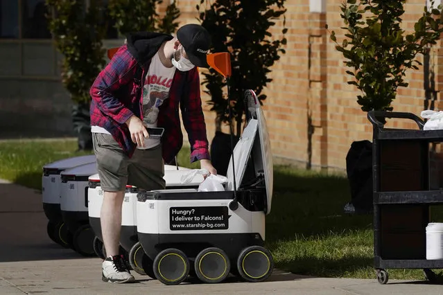Food is loaded into a robot at the Bowling Green State University campus in Bowling Green, Ohio on Thursday, October 13, 2021. Robot food delivery is no longer the stuff of science fiction. Hundreds of little robots – knee-high and able to hold around four large pizzas – are now navigating college campuses and even some city sidewalks in the U.S., the U.K. and elsewhere. While robots were being tested in limited numbers before the coronavirus hit, the companies building them say pandemic-related labor shortages and a growing preference for contactless delivery have accelerated their deployment. (Photo by Carlos Osorio/AP Photo)