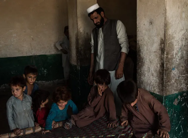 Mir Jamar, a father of 9, watches his family inside the remains of an old Soviet hotel where they have been living for the past two years, on July 15, 2017 in Rodat District, Afghanistan. Jamar moved his family after fighters with the Islamic State of Iraq and Syria – Khorasan (ISIS-K) arrived to their village in the Momand Valley in the Achin District of Nangarhar, where active fighting is taking place. (Photo by Andrew Renneisen/Getty Images)