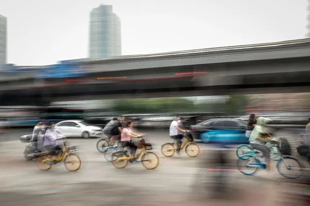 People ride bicycles in Chaoyang district, Beijing, China, 13 June 2022. Beijing announced three rounds of mass testing after a COVID-19 outbreak at a bar in Chaoyang district after the city eased restrictions. Health officials have reported 166 COVID-19 cases linked to the outbreak at a bar in the nightlife and shopping area of Sanlitun in Chaoyang district on 09 June 2022. (Photo by Mark R. Cristino/EPA/EFE)