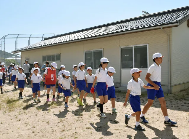 Schoolchildren leave the compound of their school during an evacuation drill in Abu town, western Japan, Sunday, June 4, 2017. The town on Japan's northwestern coast conducted the drill amid rising fear that a North Korean ballistic missile could hit Japanese soil. (Photo by Kyodo News via AP Photo)